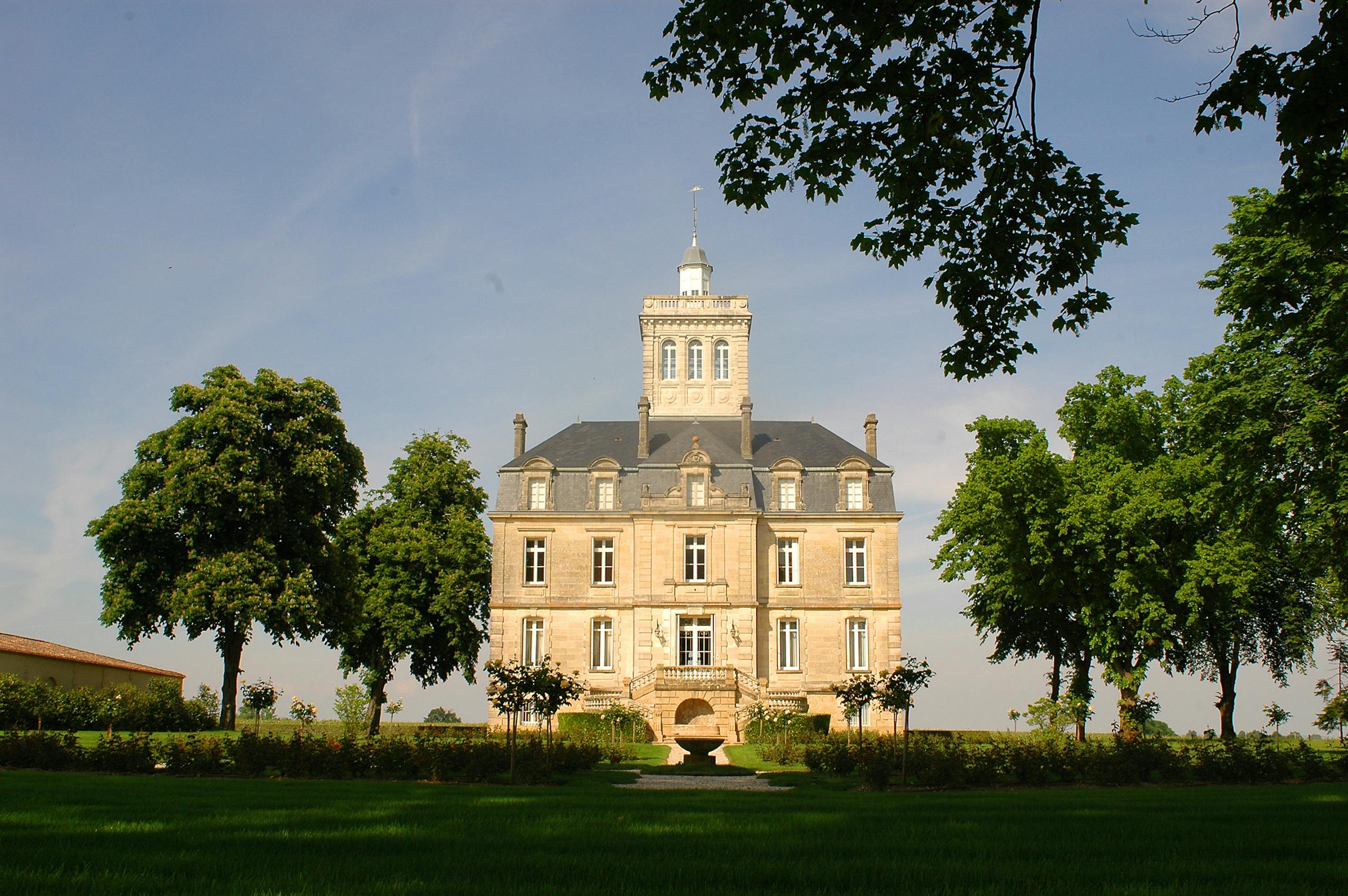 A majestic chateau with lush gardens and blue skies, capturing classic architecture.