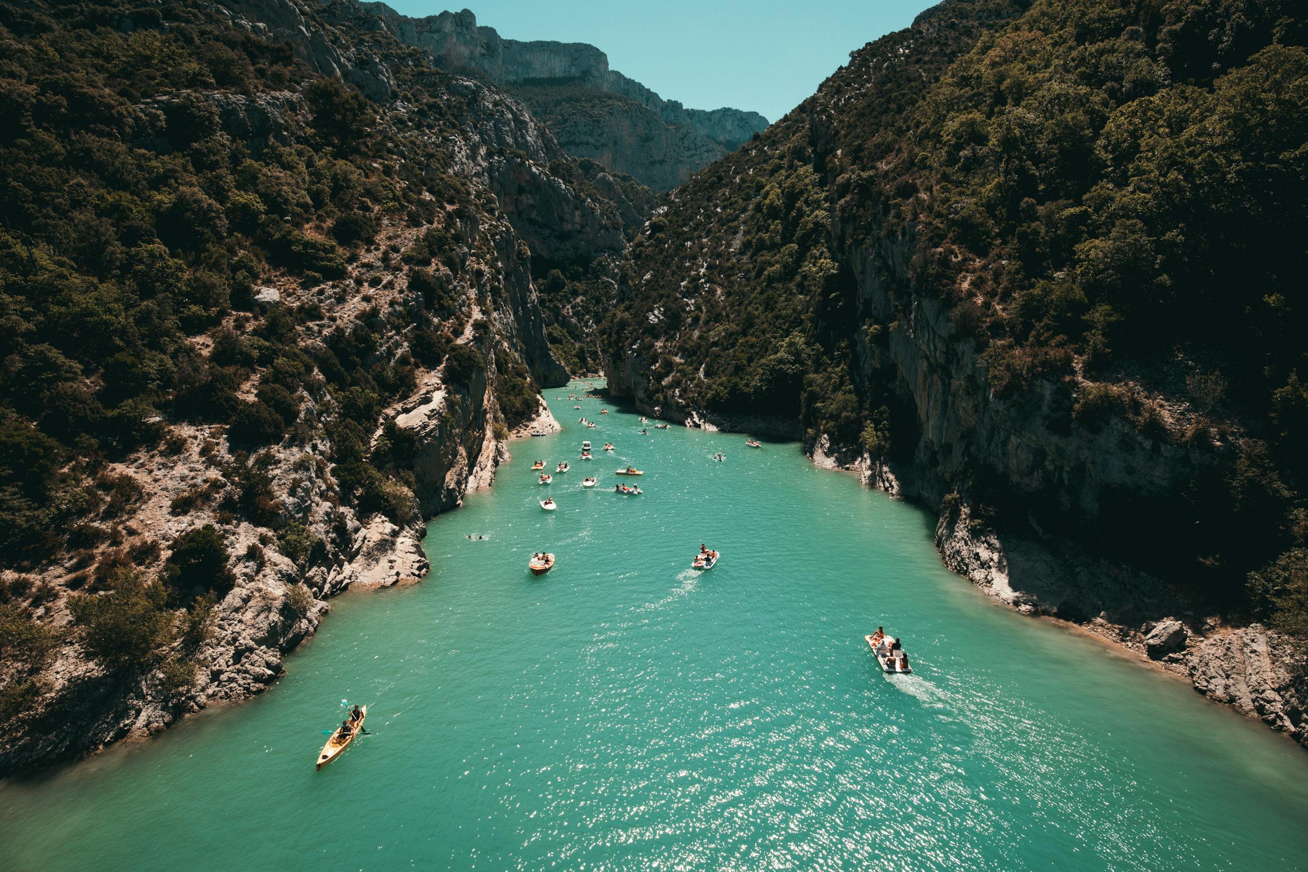 Kayakers enjoy turquoise waters surrounded by lush canyon walls, a perfect adventure setting.