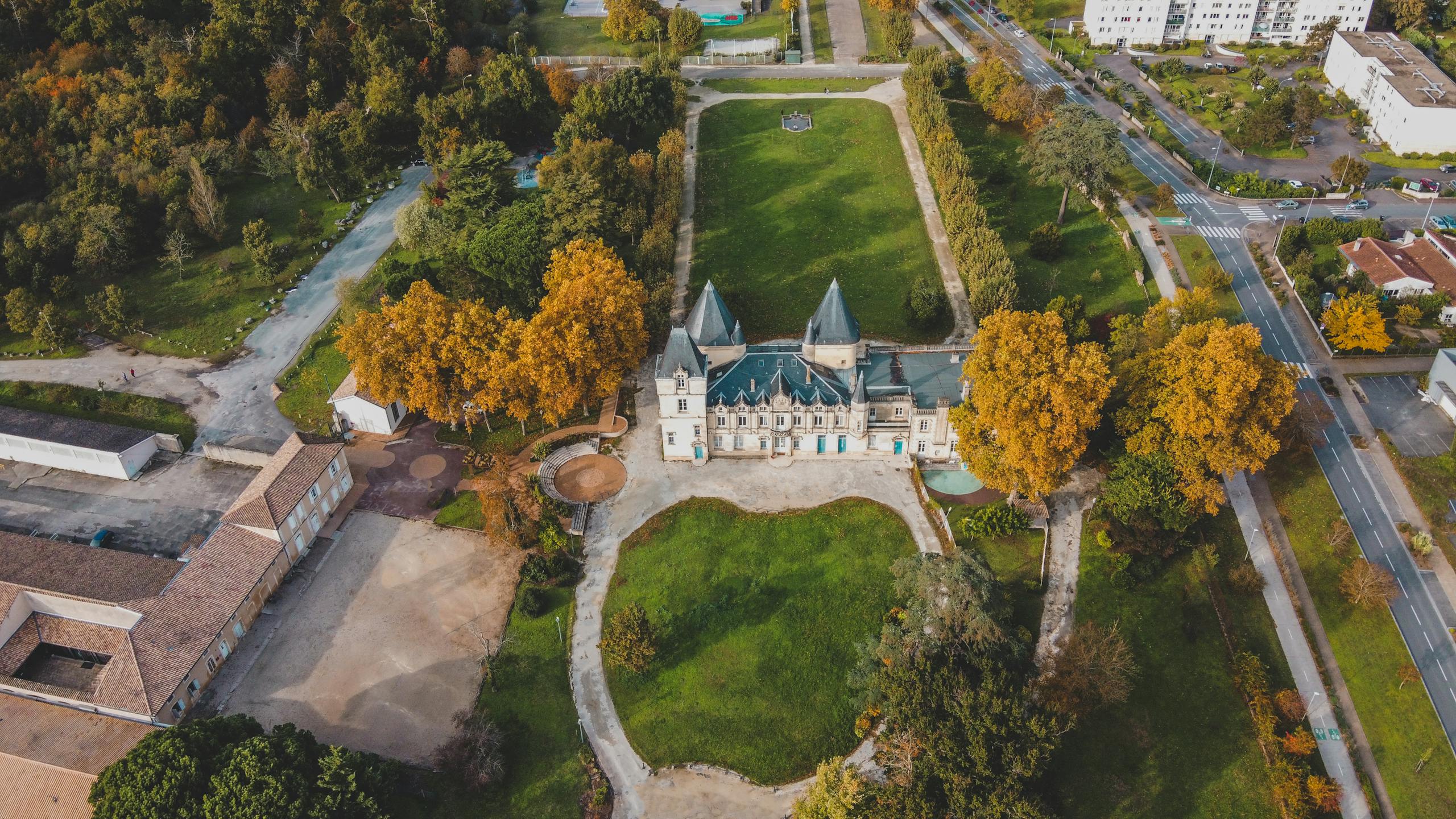 Stunning aerial photo of a chateau surrounded by lush greenery in Bordeaux, France.